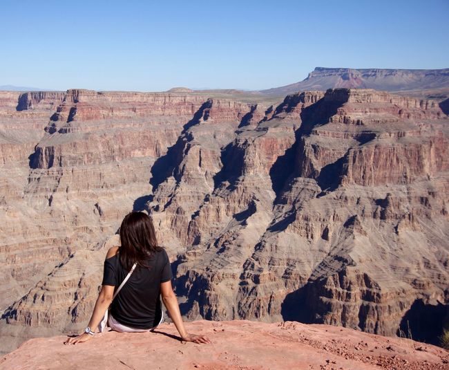Rear view of woman sitting on rock at grand canyon national park