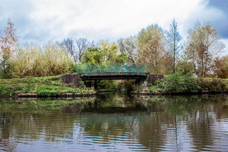 Footbridge over river in park against sky