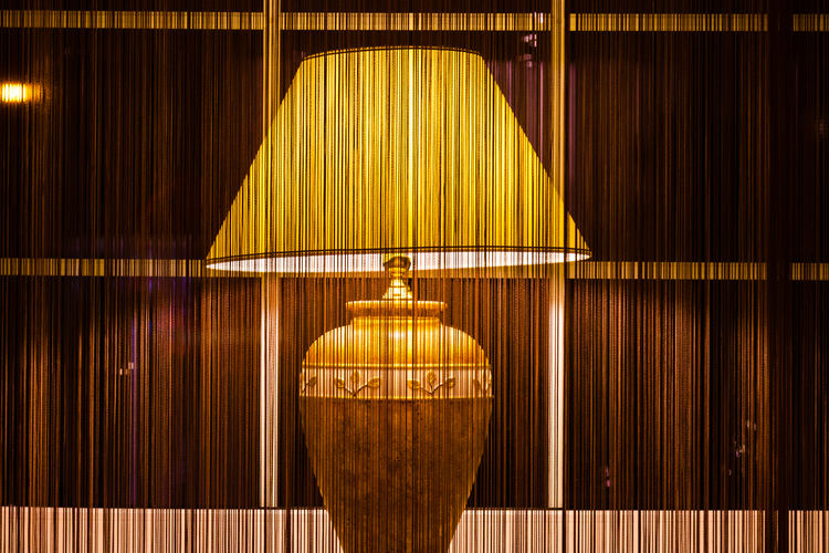 Illuminated electric lamp seen through sheer curtain