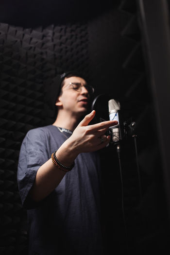 Man sings into microphone, professional recording studio, headphones. black soft walls, 
