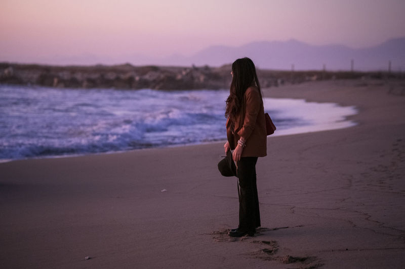 Woman standing at beach during sunset
