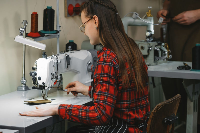 Midsection of woman using sewing machine