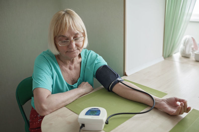 Senior woman checking blood pressure at home