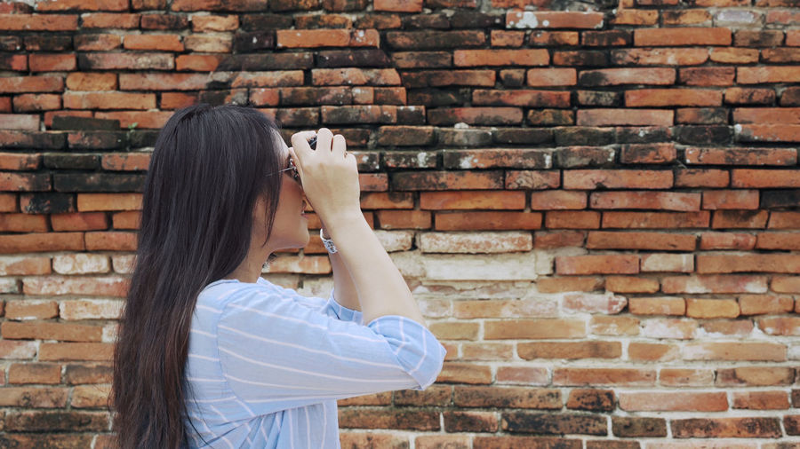 Portrait of teenage girl holding brick wall