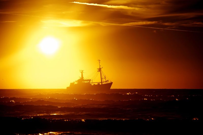 Silhouette ship in sea against sky during sunset