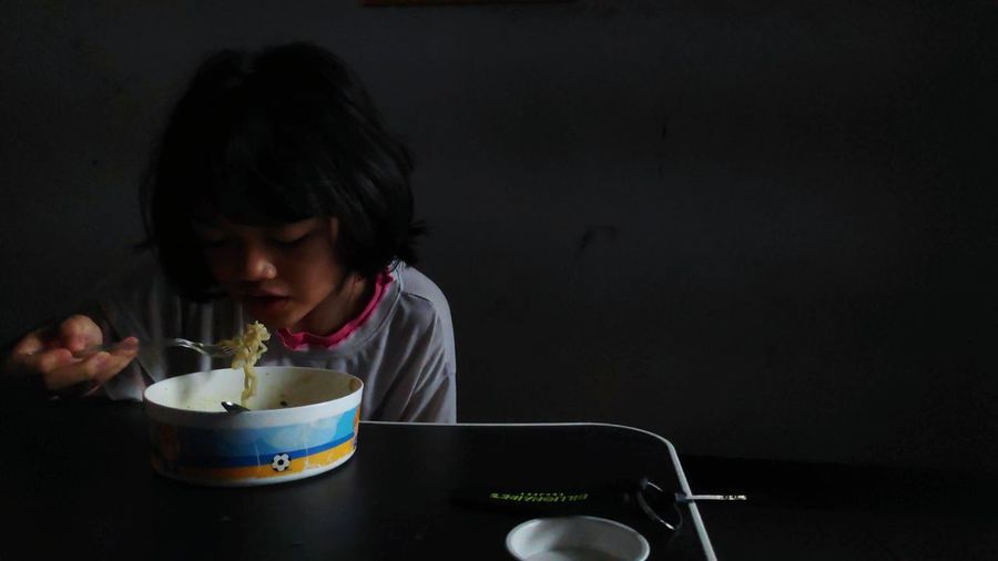 Little girl eating instant noodles in the morning