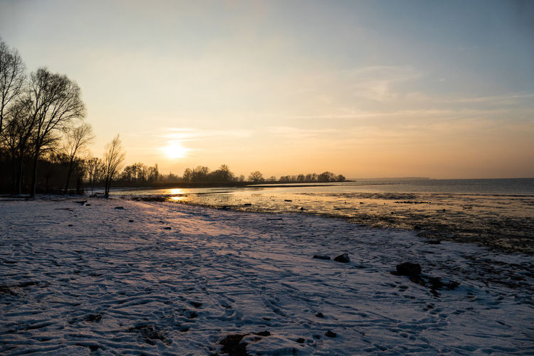 Scenic view of snow covered field against sky during sunset