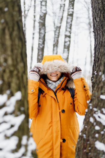 Woman standing by tree trunk during winter