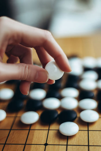Close-up of woman hand holding white stone by board game