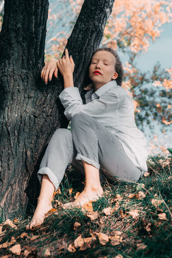 Woman sitting on tree trunk during autumn