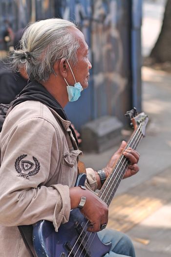 A guitarist is playing on the sidewalk