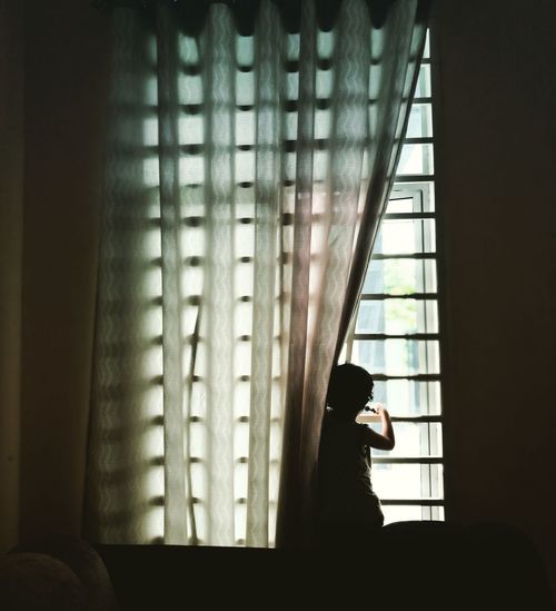 Girl looking through window at home