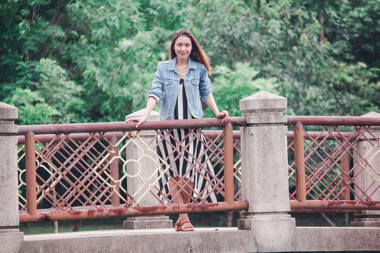 Portrait of smiling woman standing on footbridge