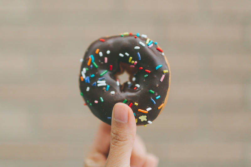 Close-up of cropped hand holding donut