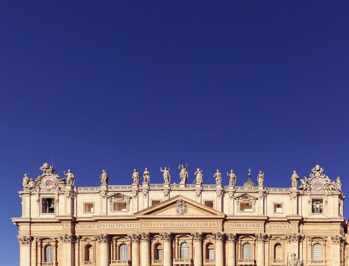 Low angle view of historical building - st. peters basilica - against blue sky, rome, vatican, italy