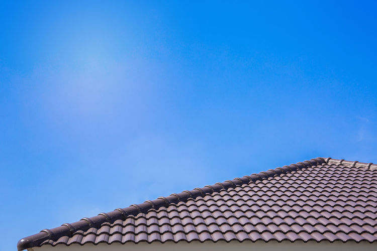 Low angle view of roof tiles against blue sky