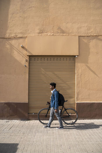 FULL LENGTH OF MAN CYCLING ON BICYCLE AGAINST WALL