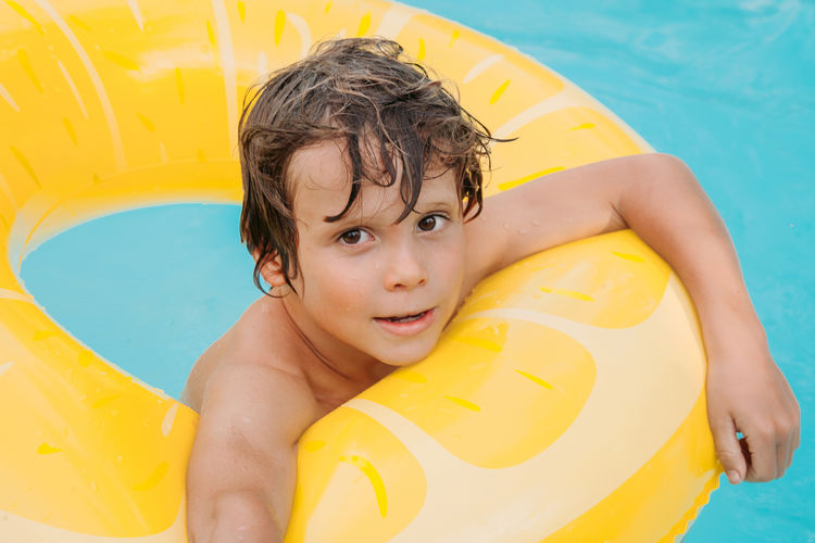 Happy holiday time. boy having fun in pool with float. face emotions. summer vibes