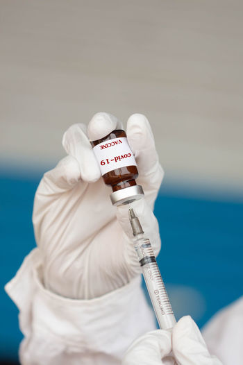 Cropped hands of doctor holding vial and syringe