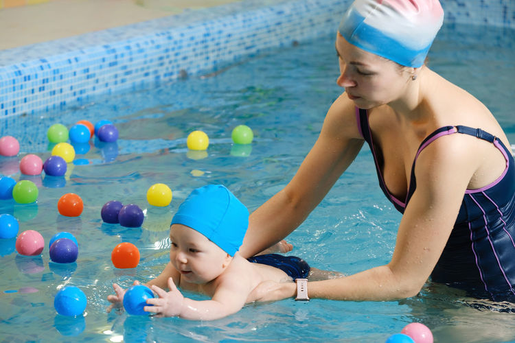 Baby boy trained to swim in water child with trainer playing having fun healthy family with infant