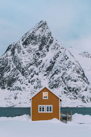 House on snow covered mountain against sky