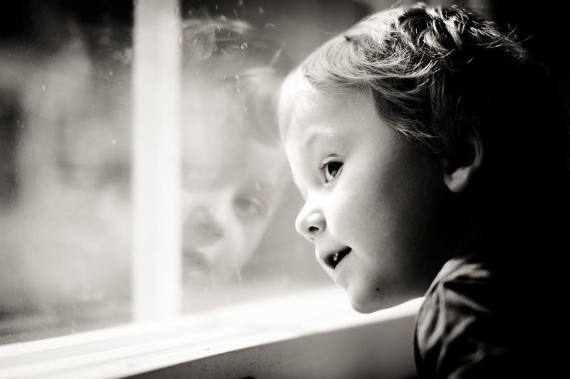 Close-up portrait of girl looking through window
