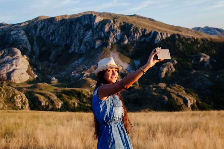 Young woman taking selfie from mobile phone on field