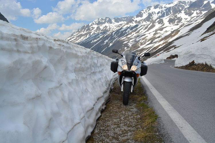 Motorcycle parked on roadside by snow retaining wall