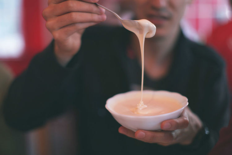 Midsection of man holding sour cream in bowl