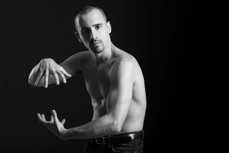 Portrait of shirtless man doing martial arts against black background