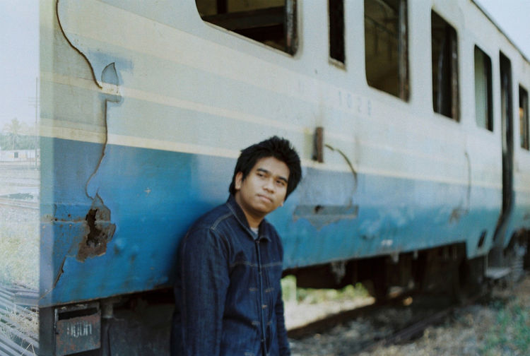 Portrait of young man standing by train