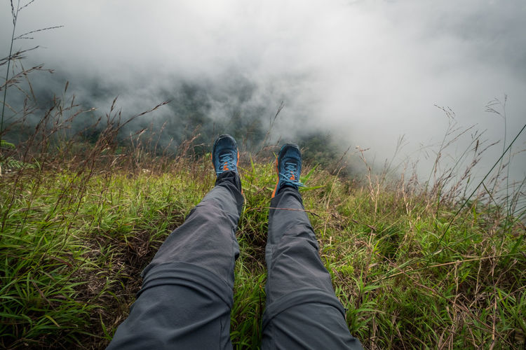 Low section of man wearing shoes on mountain during foggy weather