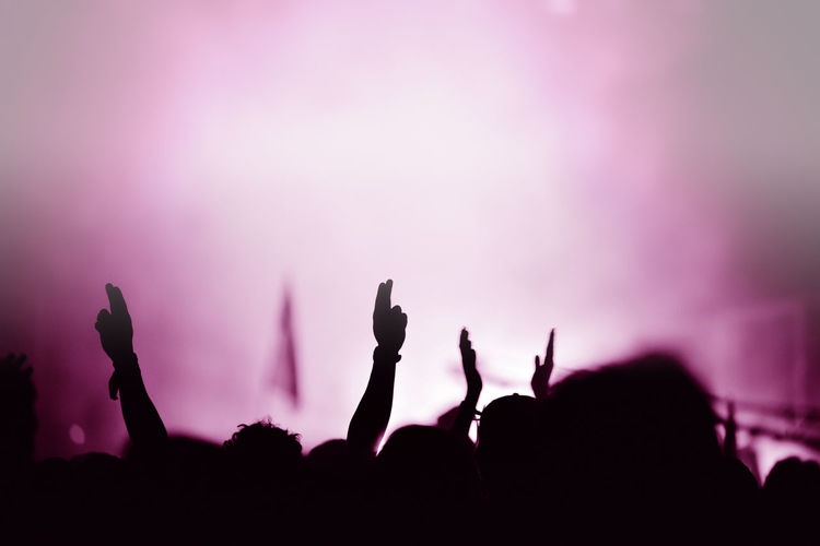 Silhouette of hands on a concert in front of bright stage lights