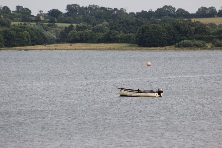 Boat floating on lake against trees