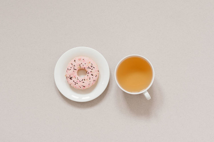 The minimalist banner coffee break. green tea in a white porcelain cup and pink donut