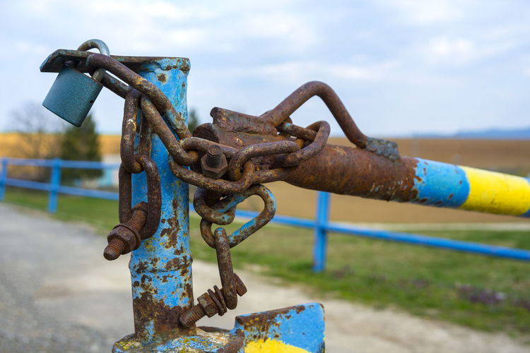 Close-up of rusty metal chain against sky