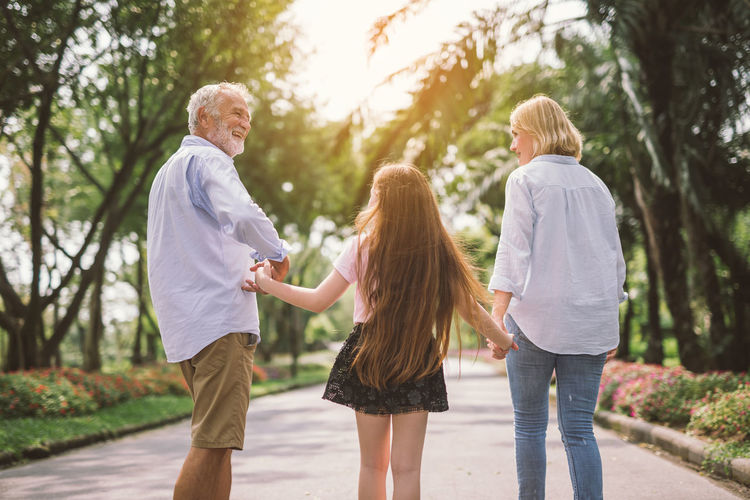 Rear view of girl with grandparents standing on road