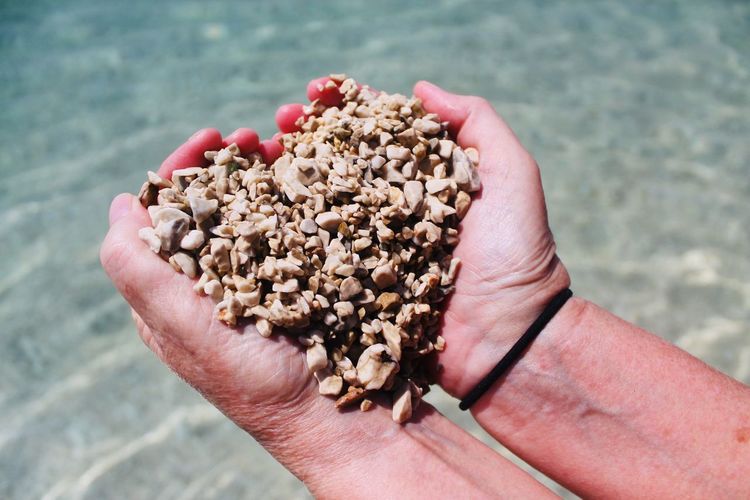 Cropped hand holding stones at beach