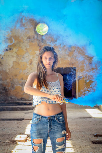 Portrait of beautiful young woman holding smoke bomb