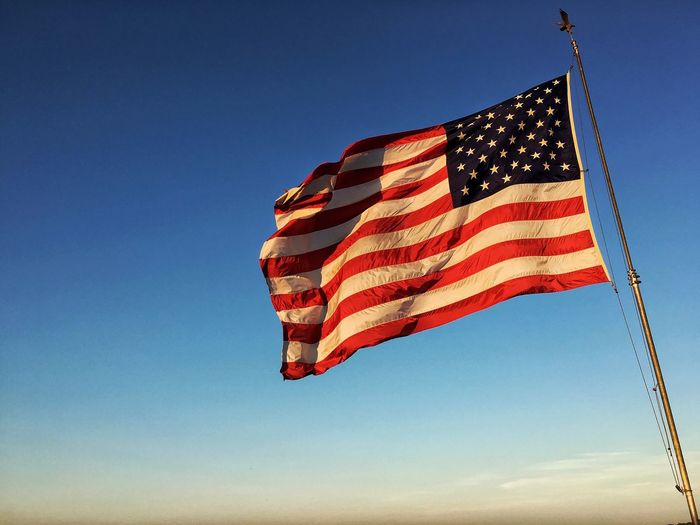 Low angle view of flag against clear blue sky