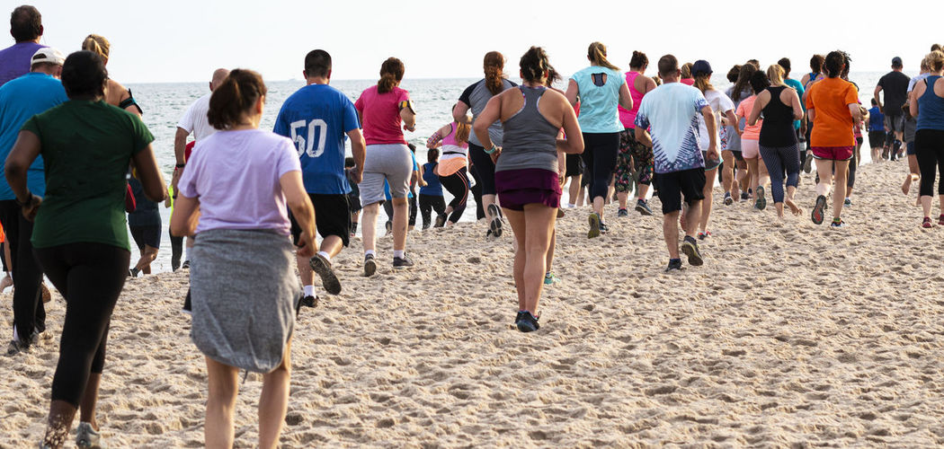 Rear view of people jogging at beach