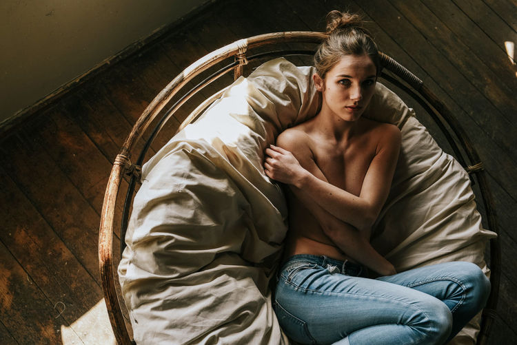Portrait of shirtless woman lying on bed