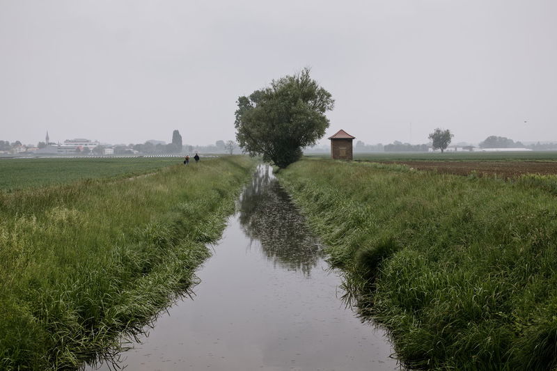Canal amidst field against clear sky
