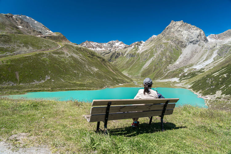Man sitting on bench against mountain range