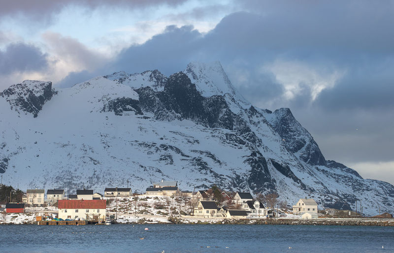Buildings by sea against sky during winter