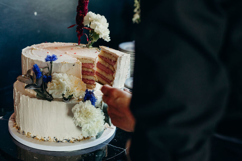 Midsection of man taking cake slice at wedding ceremony
