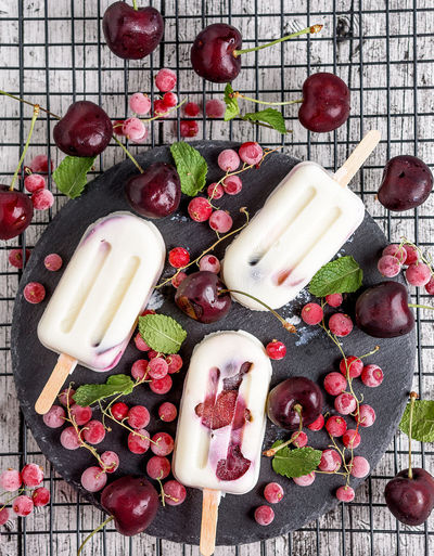 Hight angle view of cherry and redcurrant creamy mint popsicle amongst ingredients 
