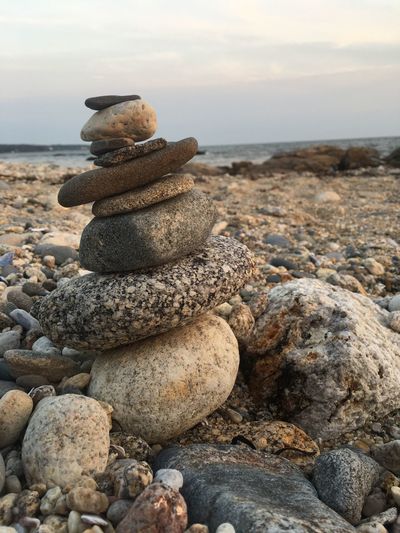 Stack of pebbles on beach against sky