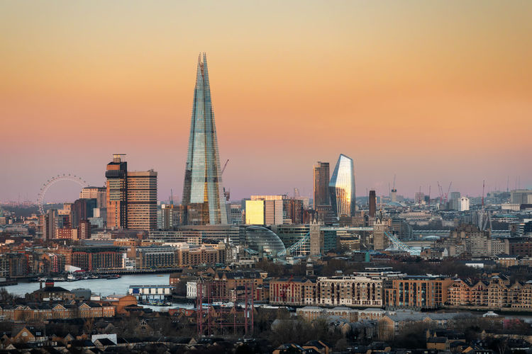 Modern buildings in city against sunset sky