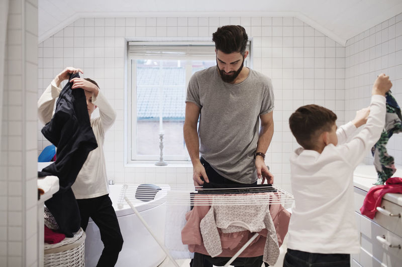 Bearded father with sons drying laundry at home